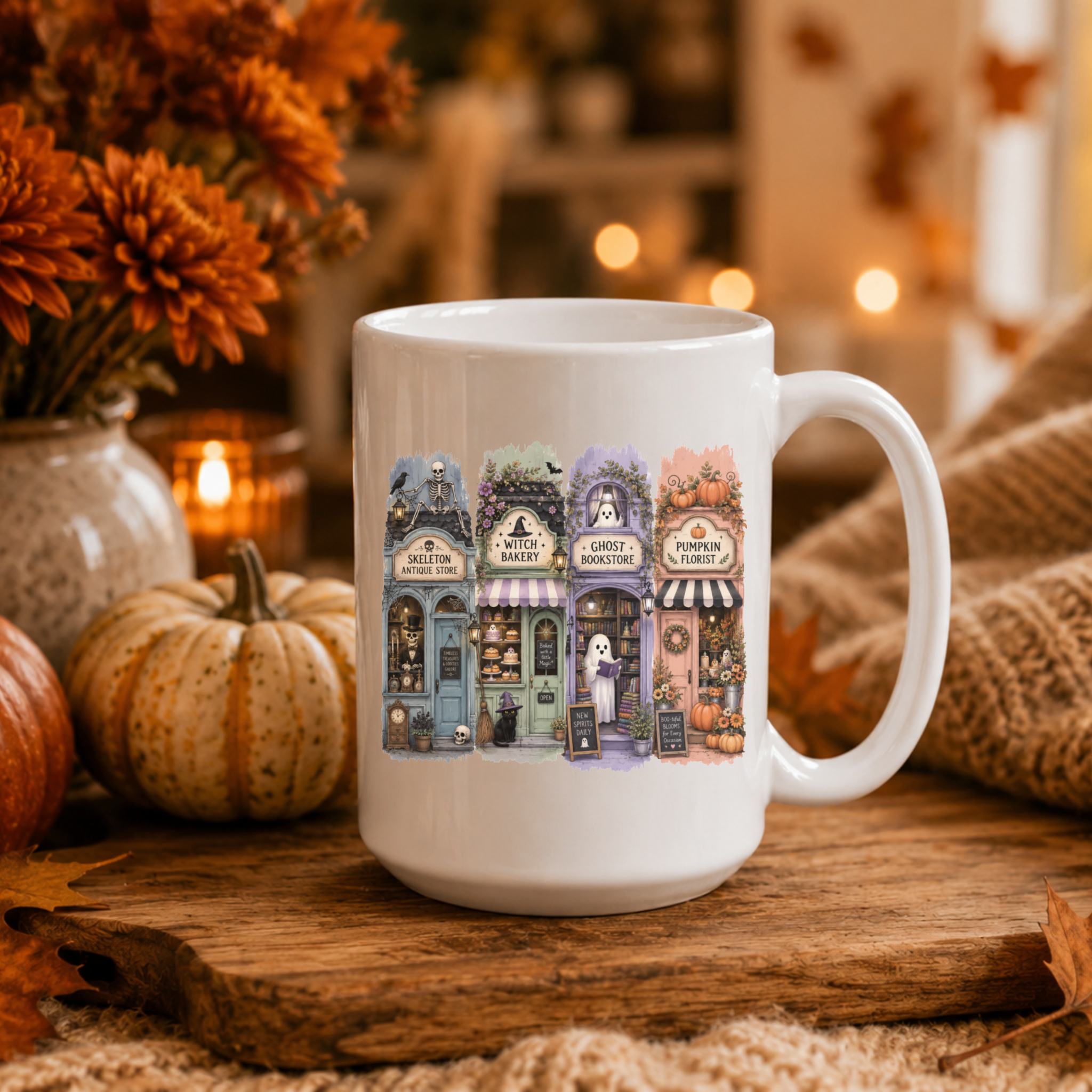 a white coffee mug with an image of a small Halloween village with 4 adorable yet spooky storefronts with ghosts, pumpkins, skeletons, and a black cat. 
