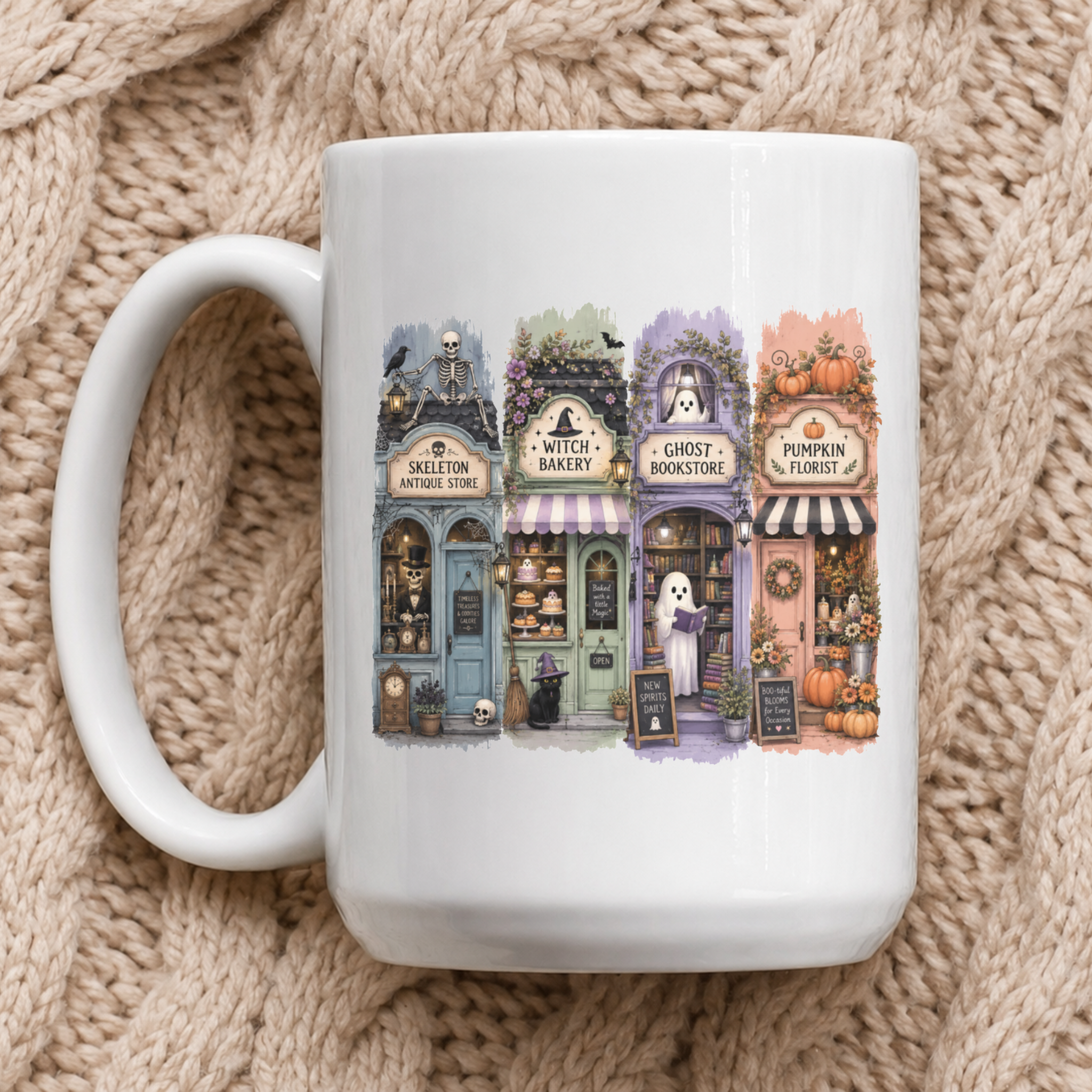 A white coffee mug with 4 haunted storefronts in an adorable Halloween village laid on a beige knit blanket.