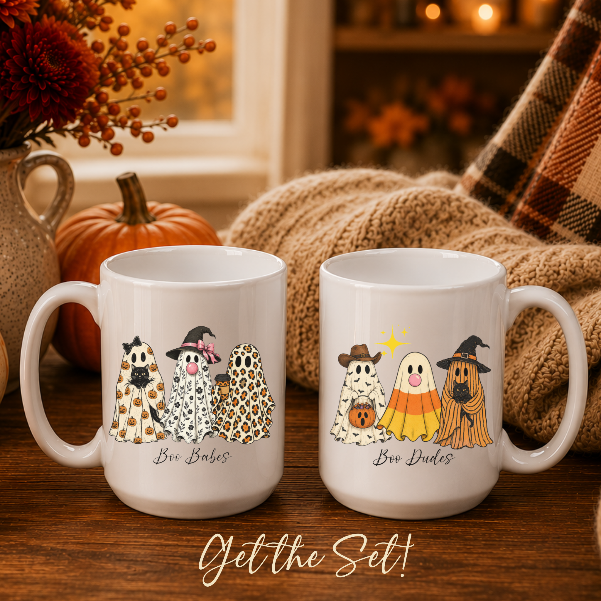 Two white ceramic mugs with Halloween-themed ghost illustrations, displayed on a wooden table with a cozy autumn background including a pumpkin, knitted blanket, and plaid scarf. The mugs are labeled 'Boo Babes' and 'Boo Dudes' with the text 'Get the Set!' at the bottom.